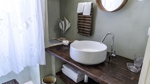 A bathroom with a round white sink, wooden countertop, and a mirror. - Casa Meliò (Polignano a Mare)