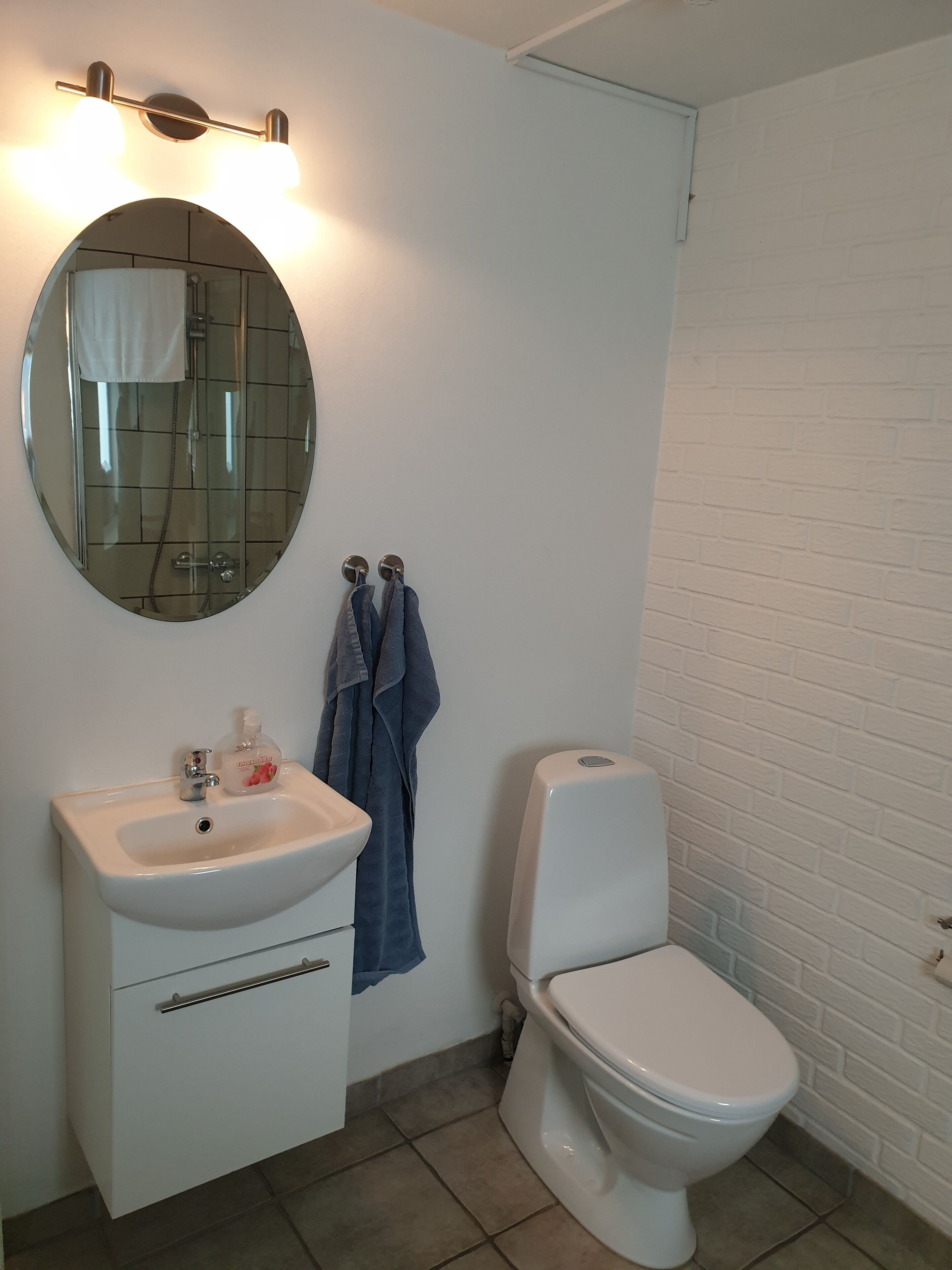 A bathroom with a white sink, mirror, and toilet.
