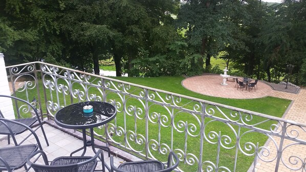 A balcony with a metal railing, a small table, and four chairs.