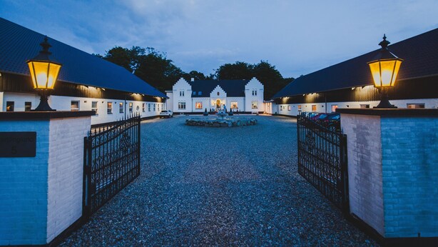 A building with a gravel driveway, two gates, and a fountain in the center. - Gørdinglund Herregård Mainbuilding (Gording)