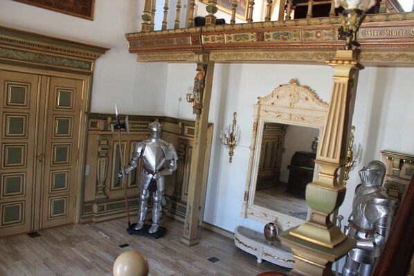 Habitació amb mobiliari ricament decorat, incloent un gran mirall i un maniquí amb armadura.