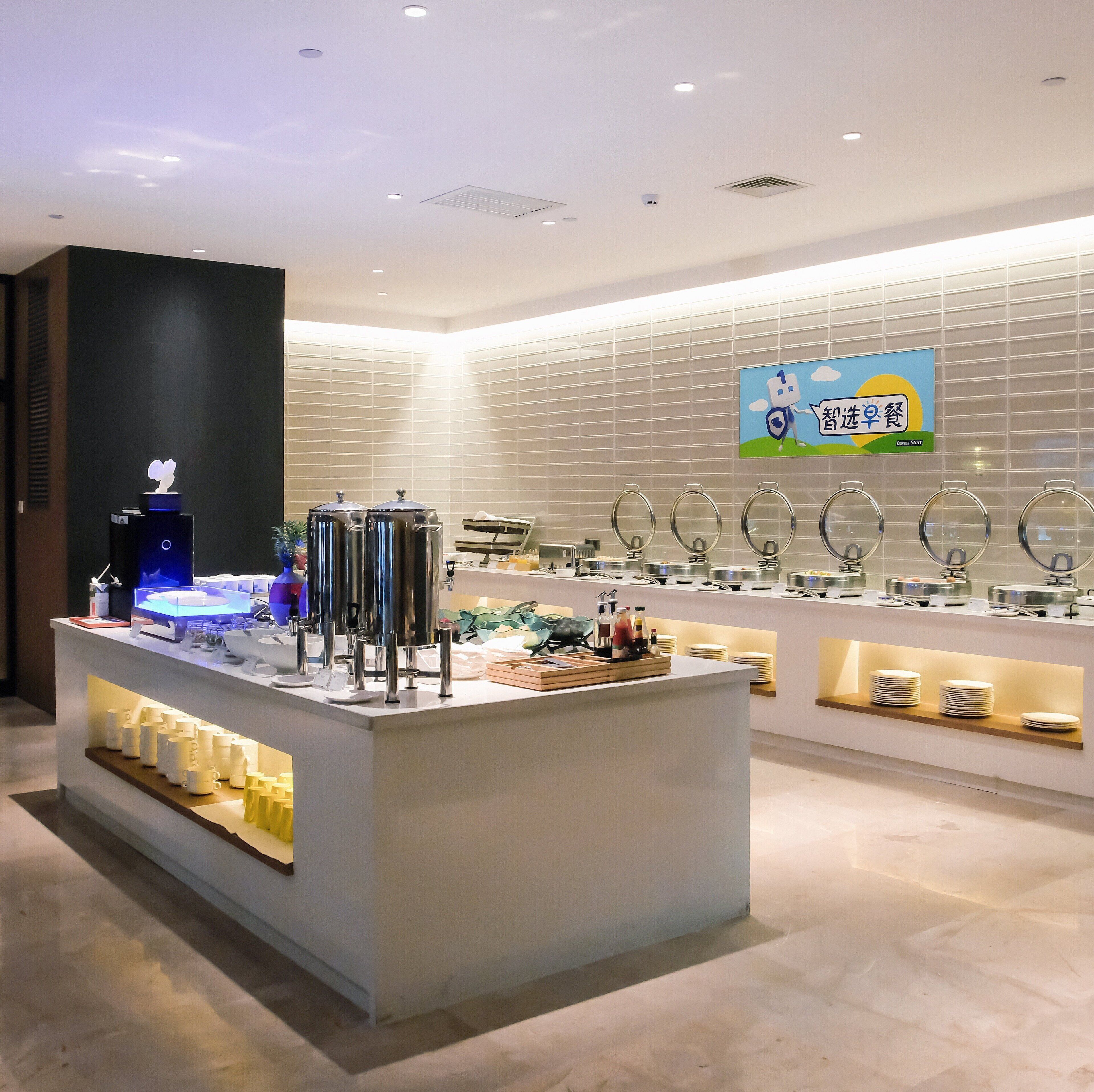 A modern breakfast area with a self-service station, a digital menu display, and a wall-mounted sign.