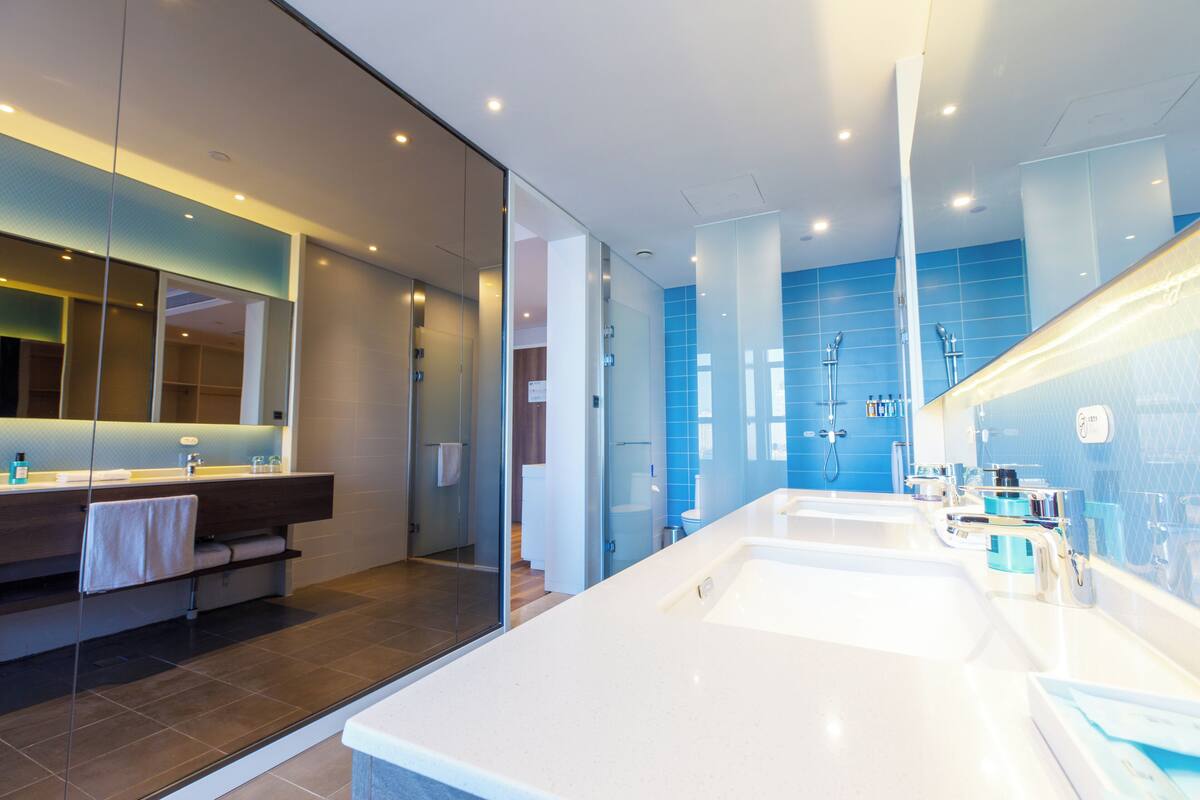 Une salle de bain moderne avec un grand lavabo blanc, une cabine de douche en verre et un miroir avec un cadre en bois.