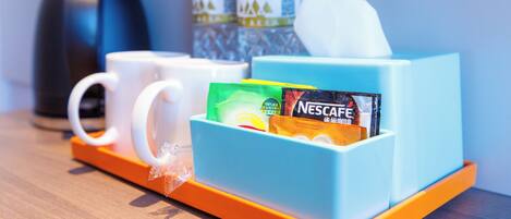 A hotel room's breakfast area with a coffee maker, two water bottles, a tissue box, and a Nescafe coffee packet.