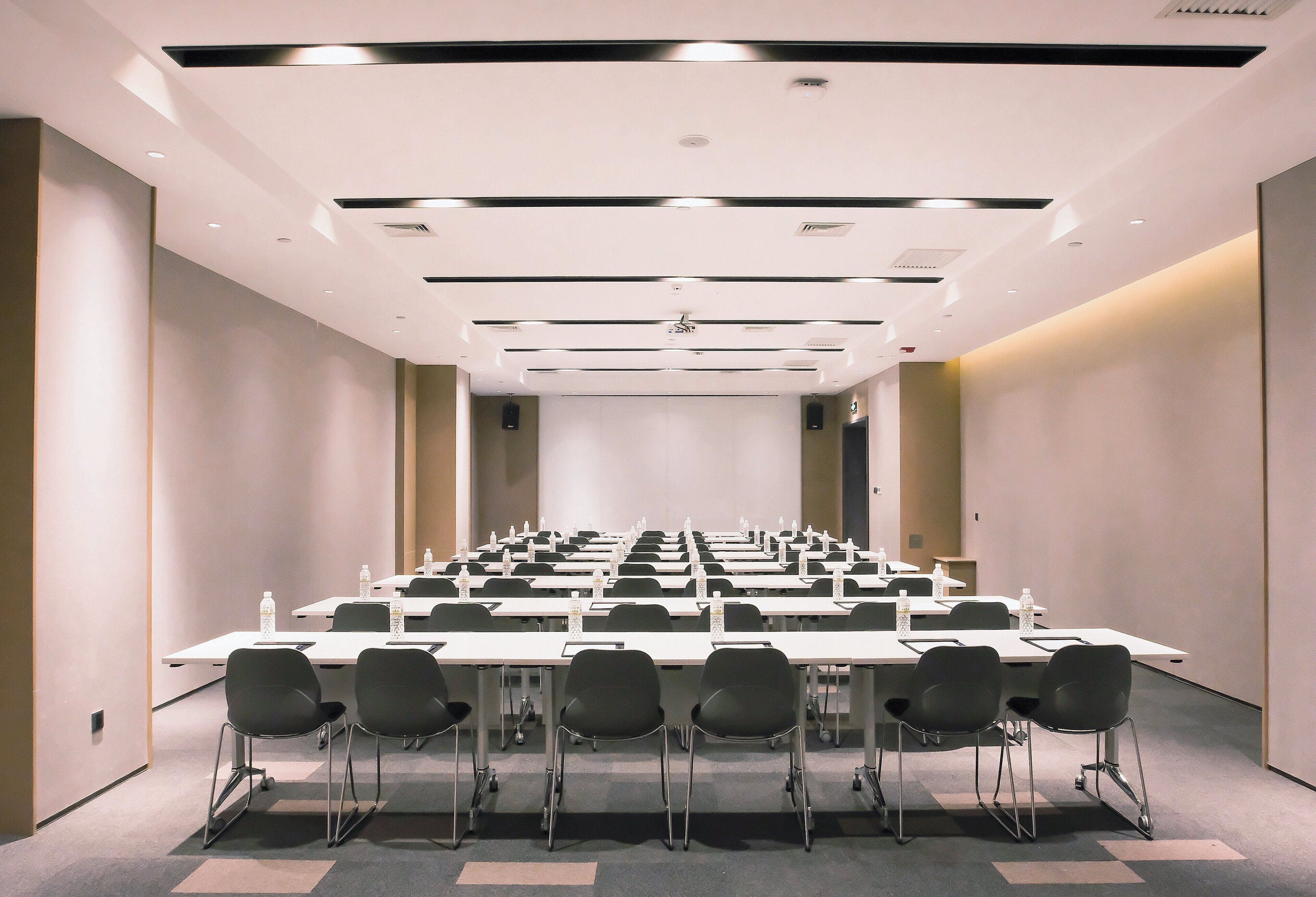 A conference room with tables and chairs, equipped with water bottles and nameplates.