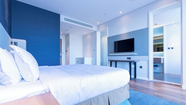 A modern hotel room with a large bed, a flat-screen TV, a desk, and a walk-in closet. - Holiday Inn Express Harbin Qunli by IHG (Harbin)