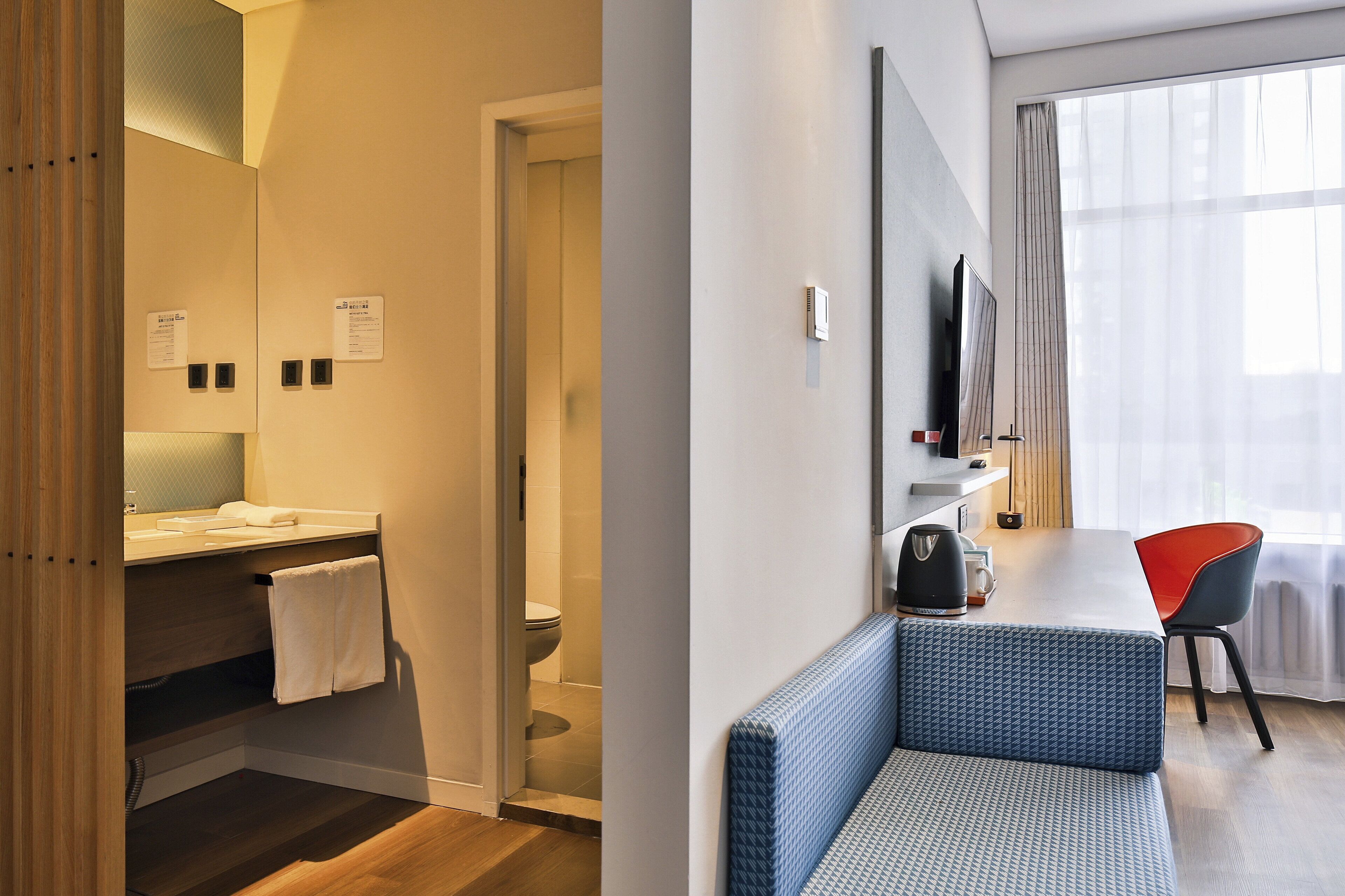 Ein Hotelzimmer mit Bad, einer Sitzecke mit Tisch und einem großen Fenster.
