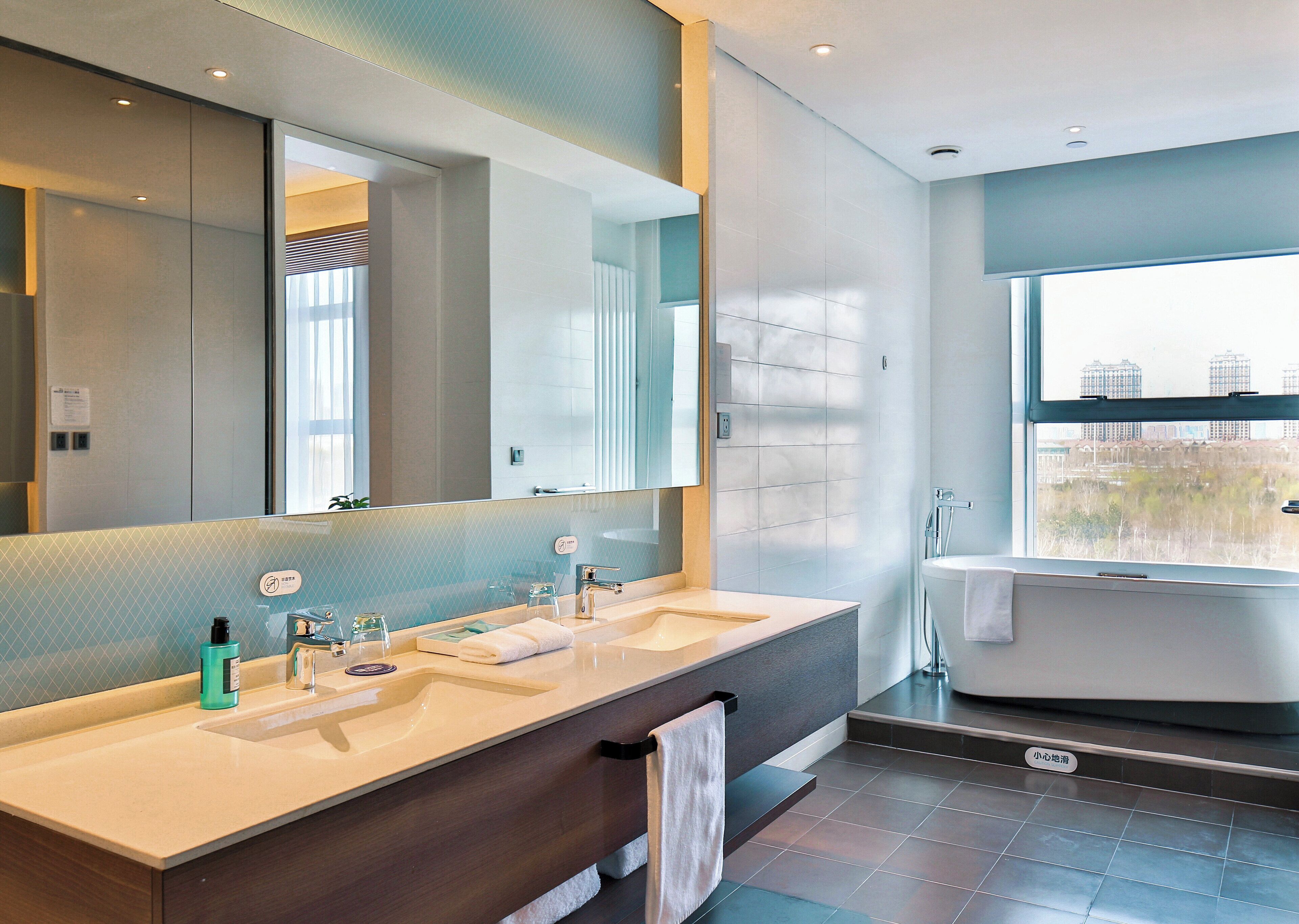 Un baño moderno con dos lavamanos, un espejo grande y una bañera.