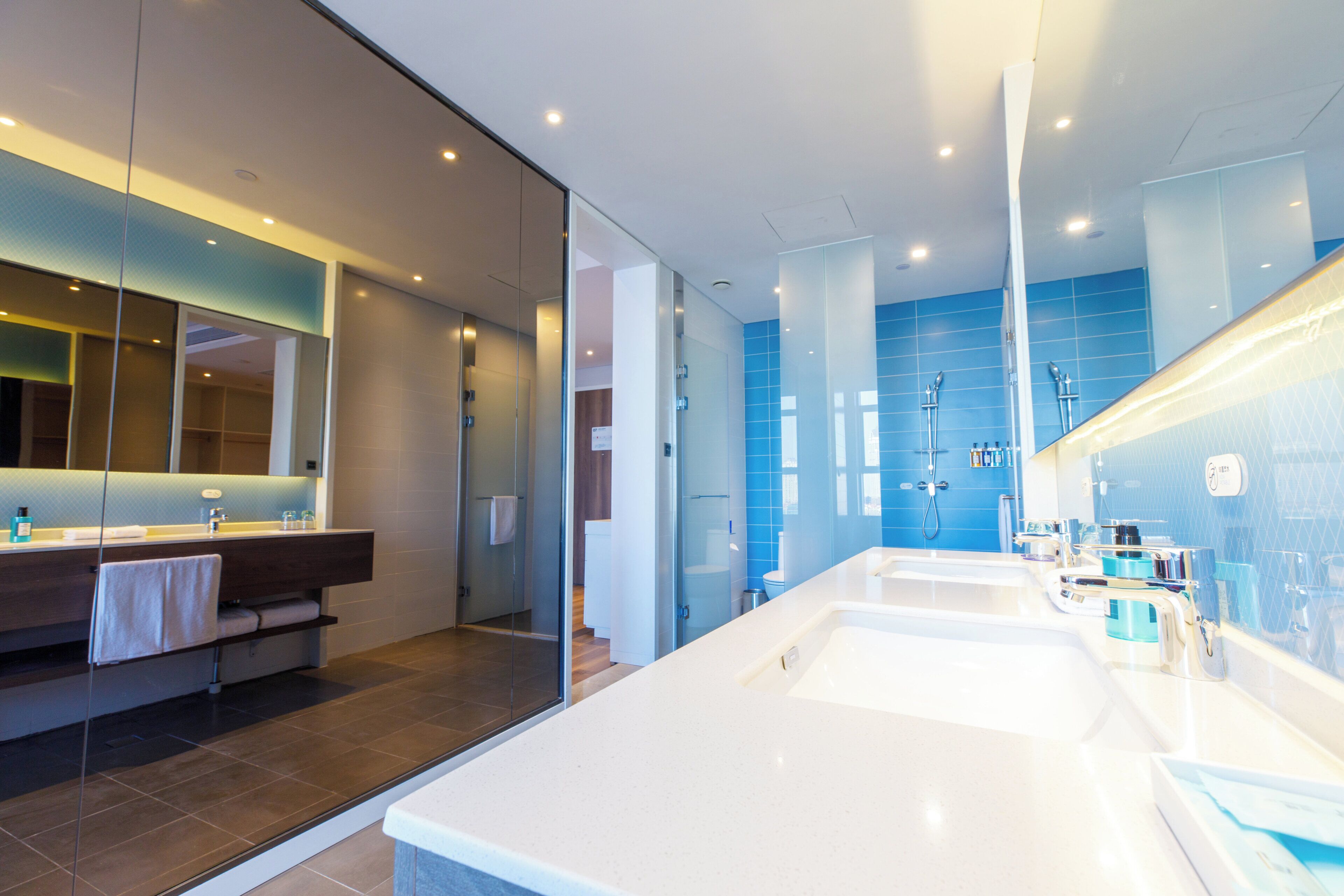 Un baño moderno con un espejo grande, dos lavamanos y una zona de ducha.