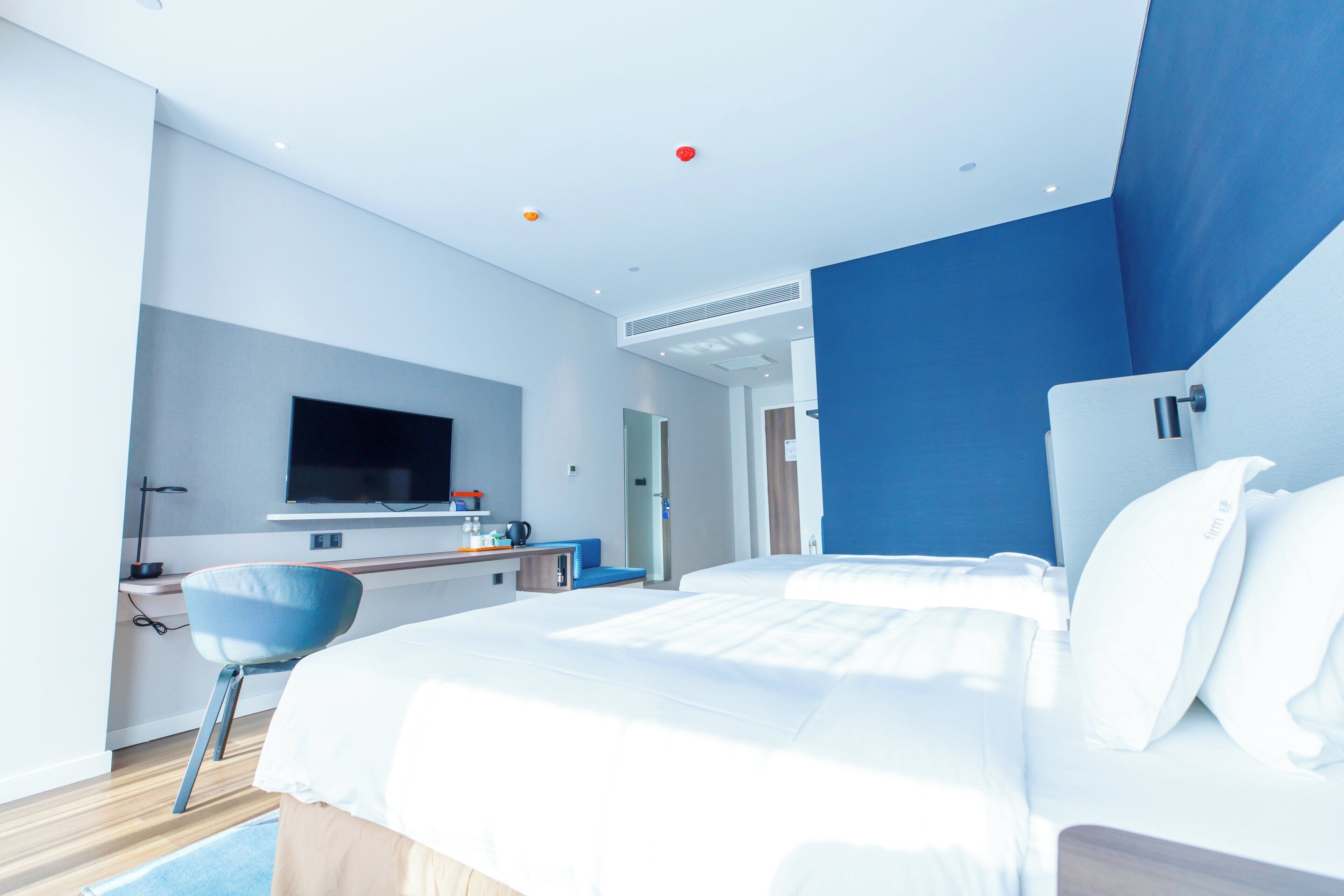 A modern hotel room with a large bed, a desk, and a television.