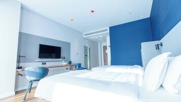 A modern hotel room with a large bed, a desk, and a television.