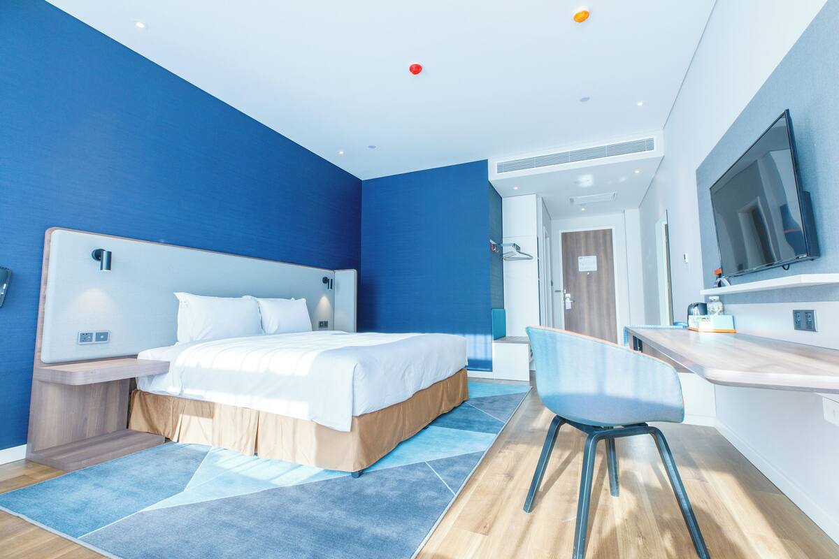 Une chambre d’hôtel moderne équipée d’un grand lit, d’un bureau, d’une chaise et d’une télévision.