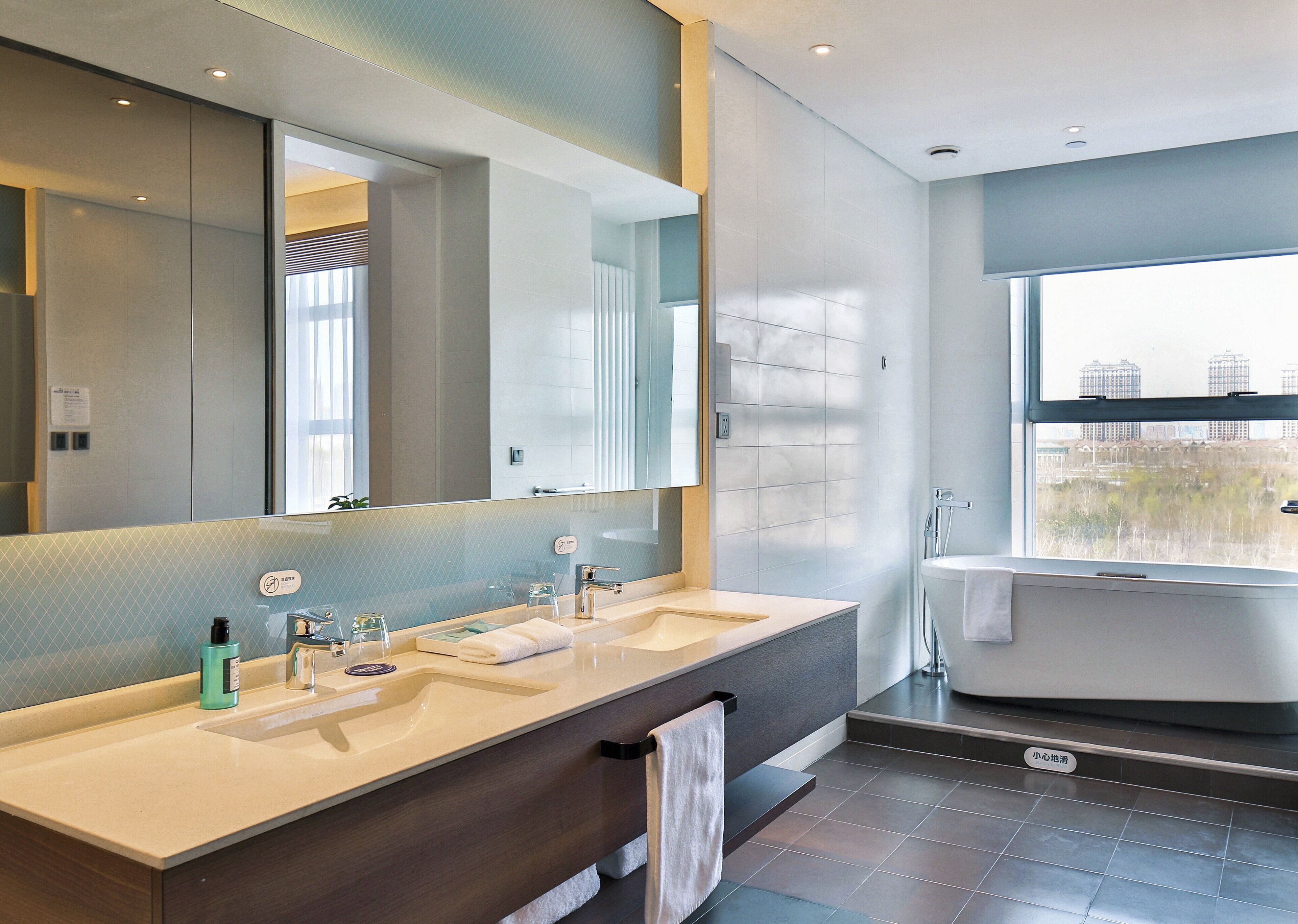 Un bagno moderno con due lavabi, uno specchio grande e una vasca da bagno.