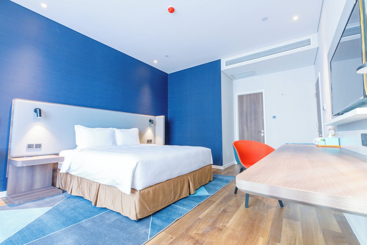 Habitació d'hotel moderna amb un llit gran, una taula i una cadira.