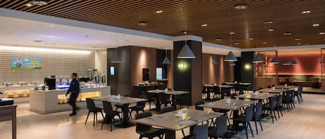A modern restaurant with a wooden ceiling, multiple tables, and chairs.