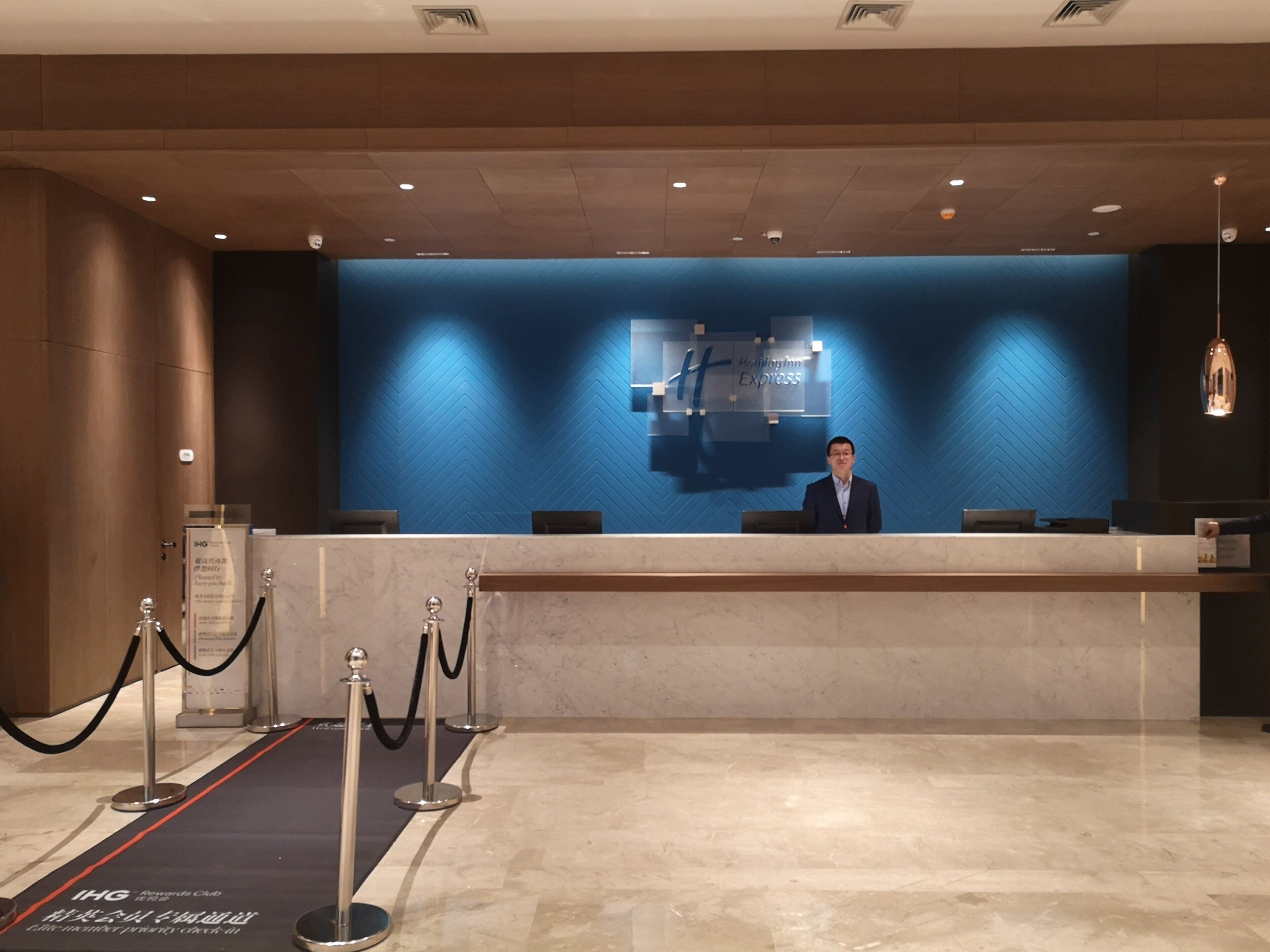A hotel reception desk with a blue wall and a sign that reads 'Holiday Inn Express.'