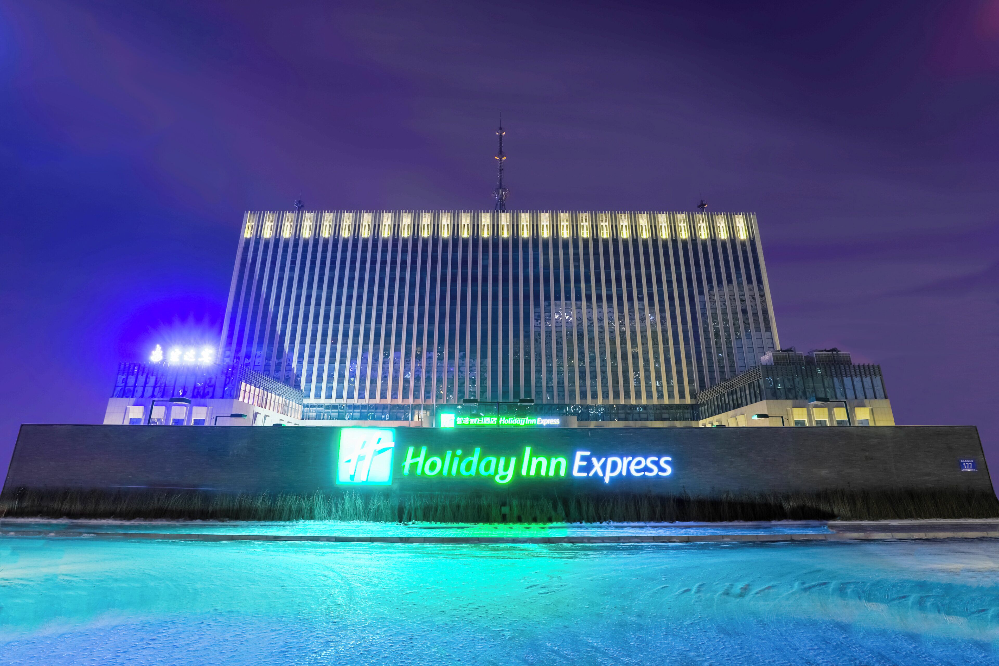 Un hotel Holiday Inn Express con fachada moderna y un letrero iluminado grande.