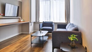 A modern living room with a flat-screen TV, a sofa, a chair, and a coffee table. - Holiday Inn Express Harbin Qunli by IHG (Harbin)