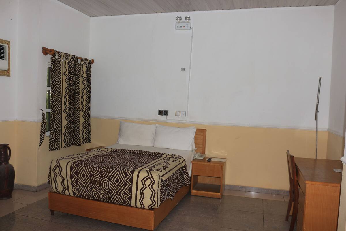 Une chambre à coucher comprenant un lit, une table de chevet, une chaise et un bureau.