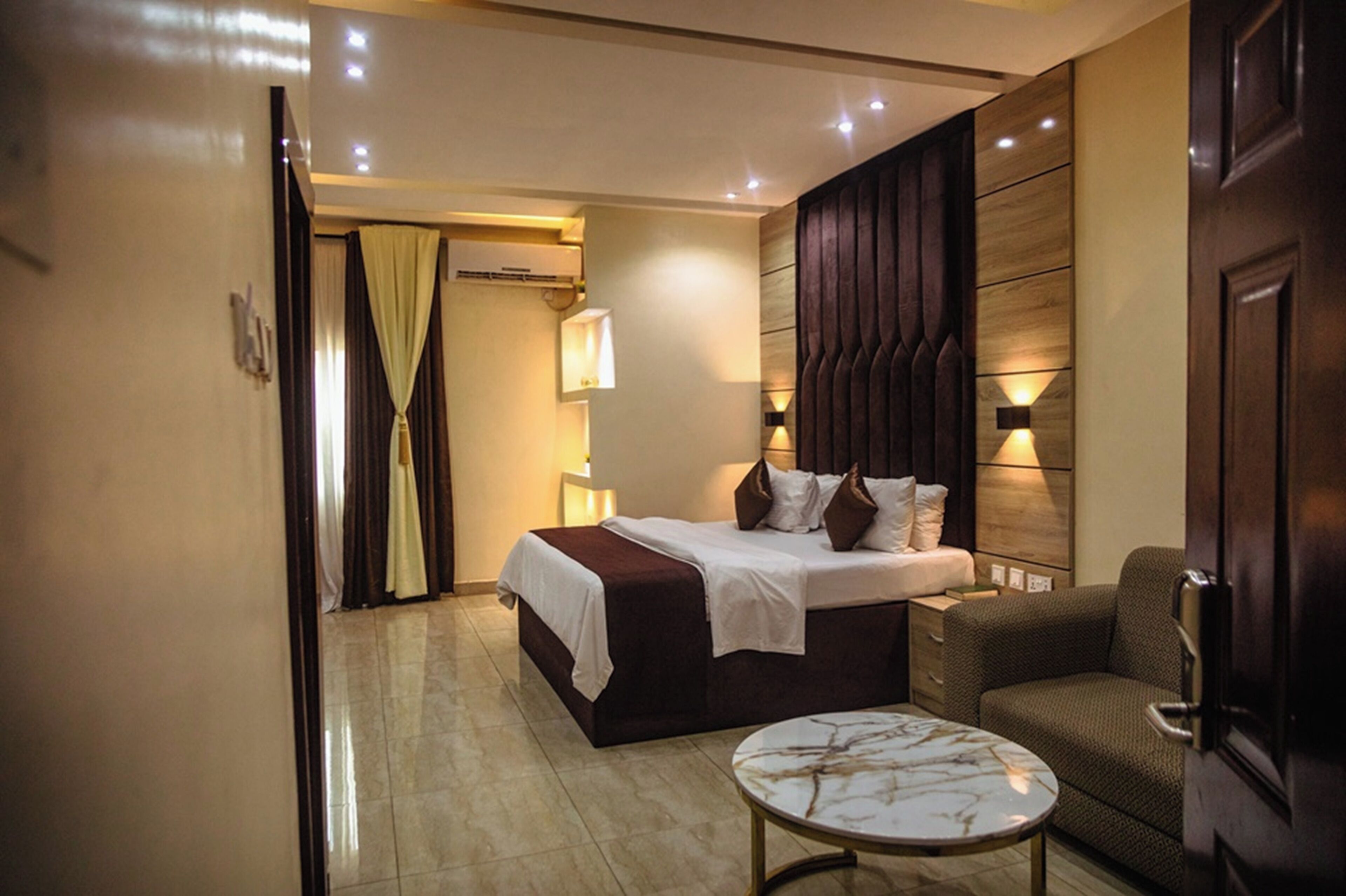 A hotel room with a bed, bedside table, and a chair.
