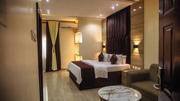 A hotel room with a bed, bedside table, and a chair.
