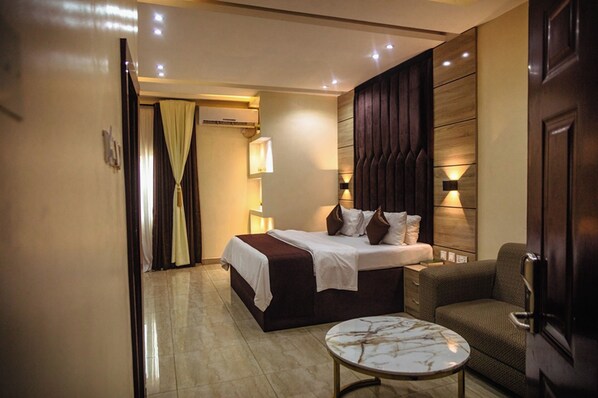 Una habitación de hotel con cama, mesita de noche y una silla.