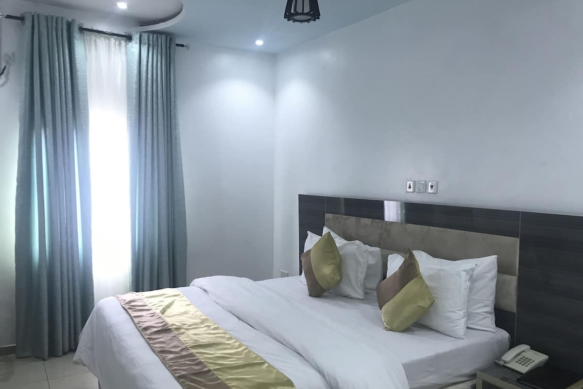 Ein modernes Hotelzimmer mit einem großen Bett, einem Nachttischtelefon und einem Beistelltisch.
