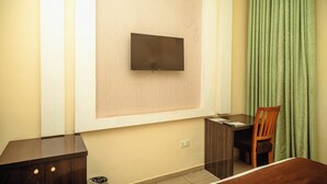 Une chambre d’hôtel équipée d’un téléviseur à écran plat fixé au mur, d’un bureau en bois, d’une chaise et d’un lit.
