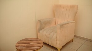 Une pièce d’angle avec un fauteuil de couleur claire et une petite table ronde.