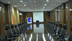 A conference room with a long table and chairs, a projector screen, and a whiteboard.