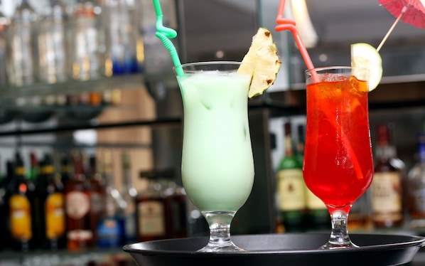 Deux cocktails sur un plateau, avec un arrière-plan flou composé de bouteilles.