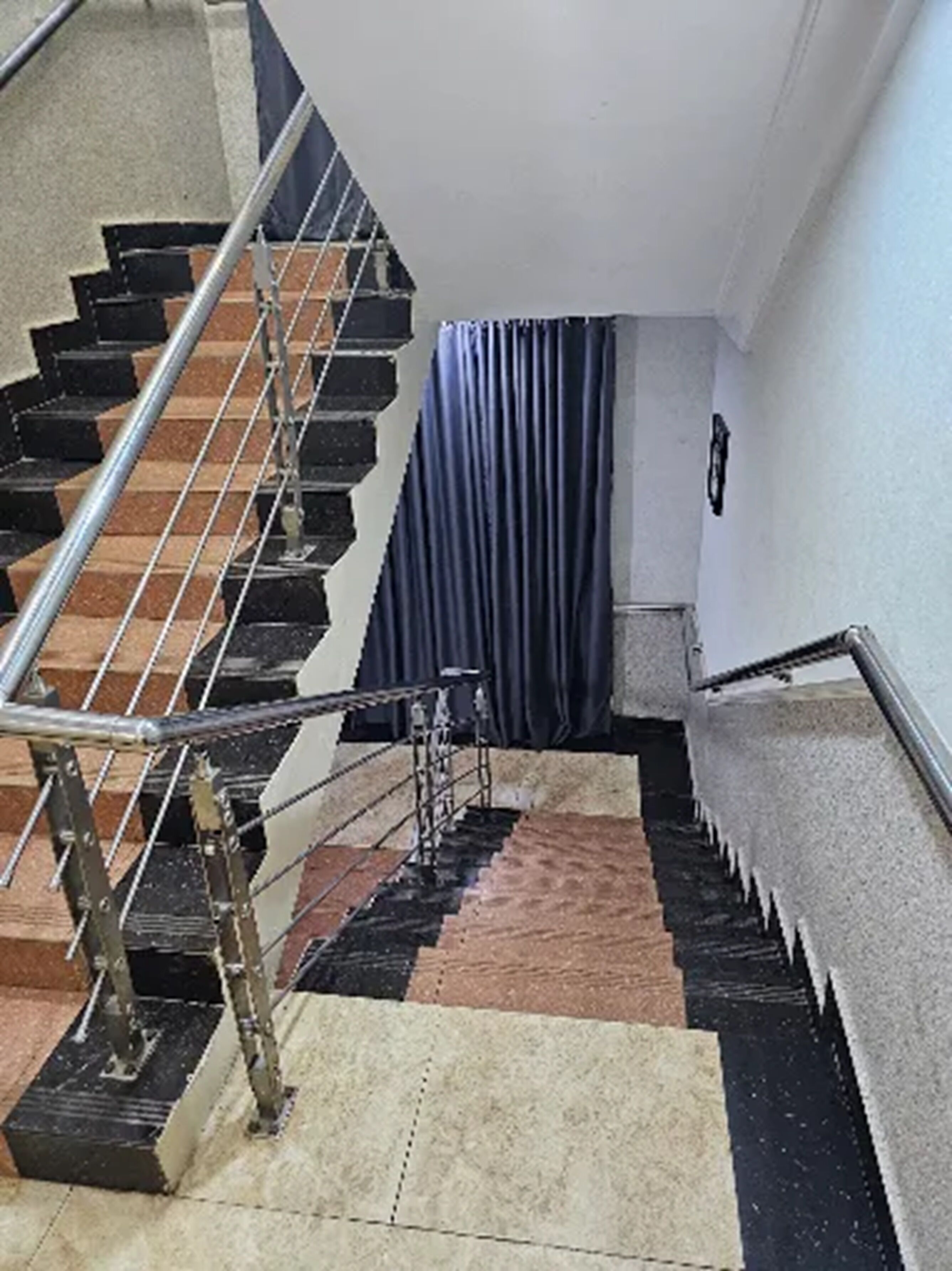 Una escalera con barandas metálicas y suelo estampado.