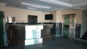 A lobby with a reception desk, a flat-screen TV, and a staircase. - Modroy Hotel and Suites (Abeokuta)