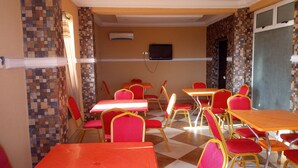 A dining area with checkered flooring, red chairs, and orange tables. - Modroy Hotel and Suites (Abeokuta)