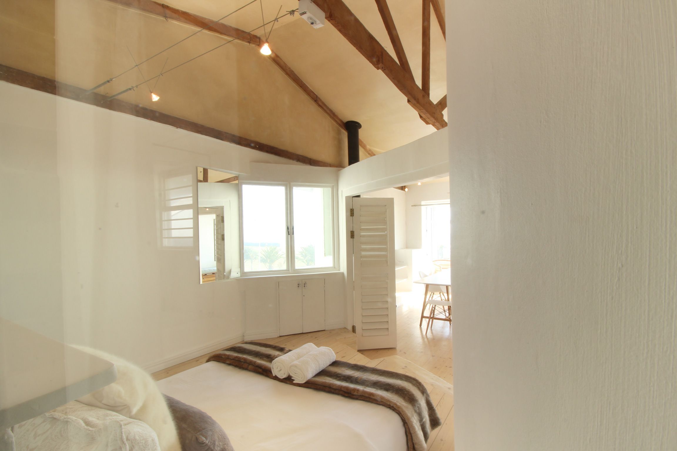 A bedroom with a large bed, a mirror, and a window.