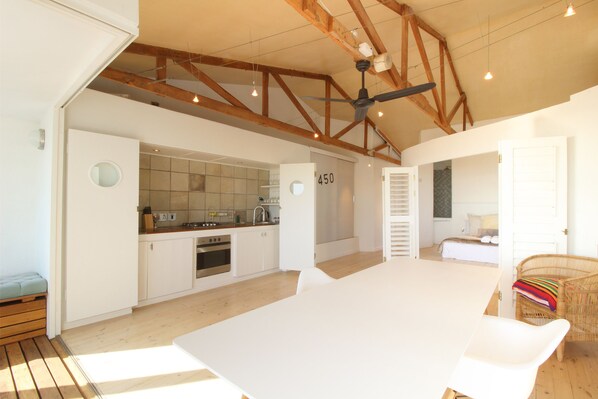 A spacious kitchen with white cabinets, a large island, and a ceiling fan. - Vredenhof 7 - Adults Only (Cape Town)