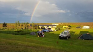 A campsite with tents, a yellow van, and a building in the background. - Fosshóll Guesthouse (Laugar)