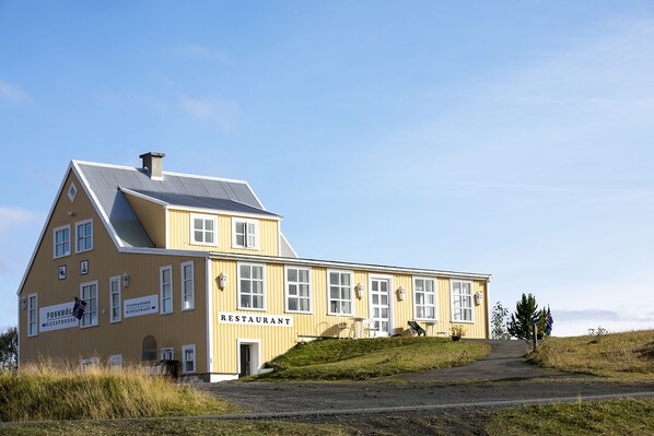 Um edifício amarelo com uma placa que diz 'FOSSHOL GUESTHOUSE RESTAURANT'.
