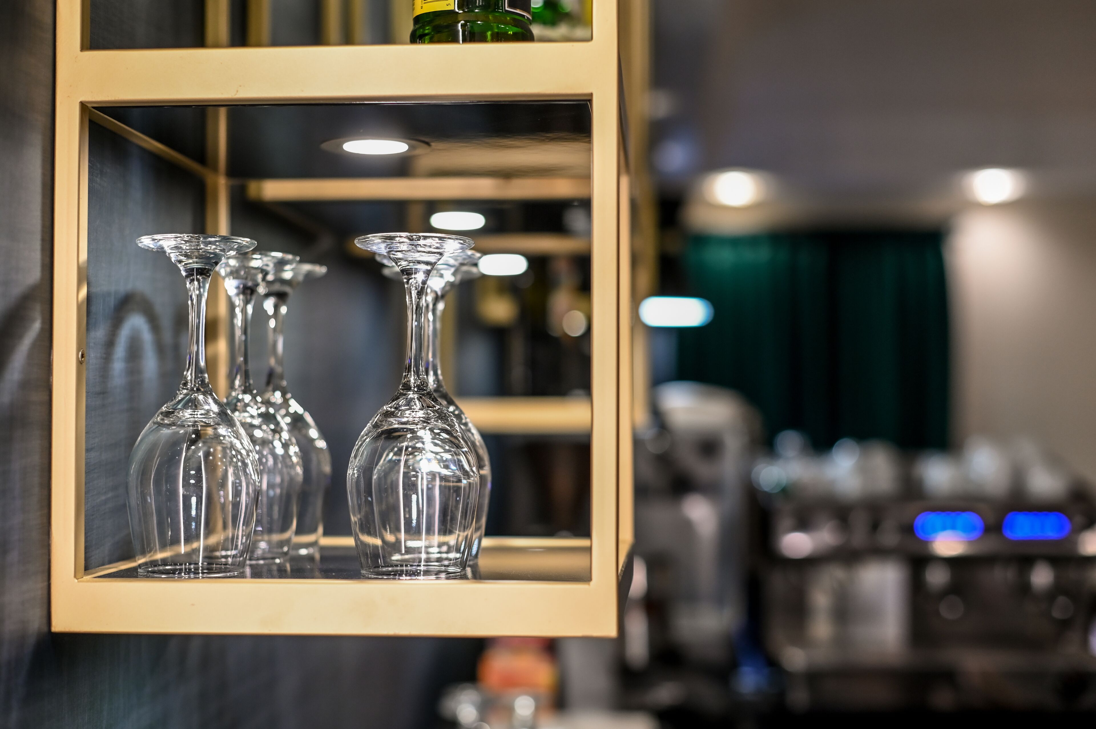 Une composition encadrée présentant des verres à vin en verre transparent, le tout dans un cadre doré réfléchissant, le décor étant un fond sombre avec un intérieur flou.