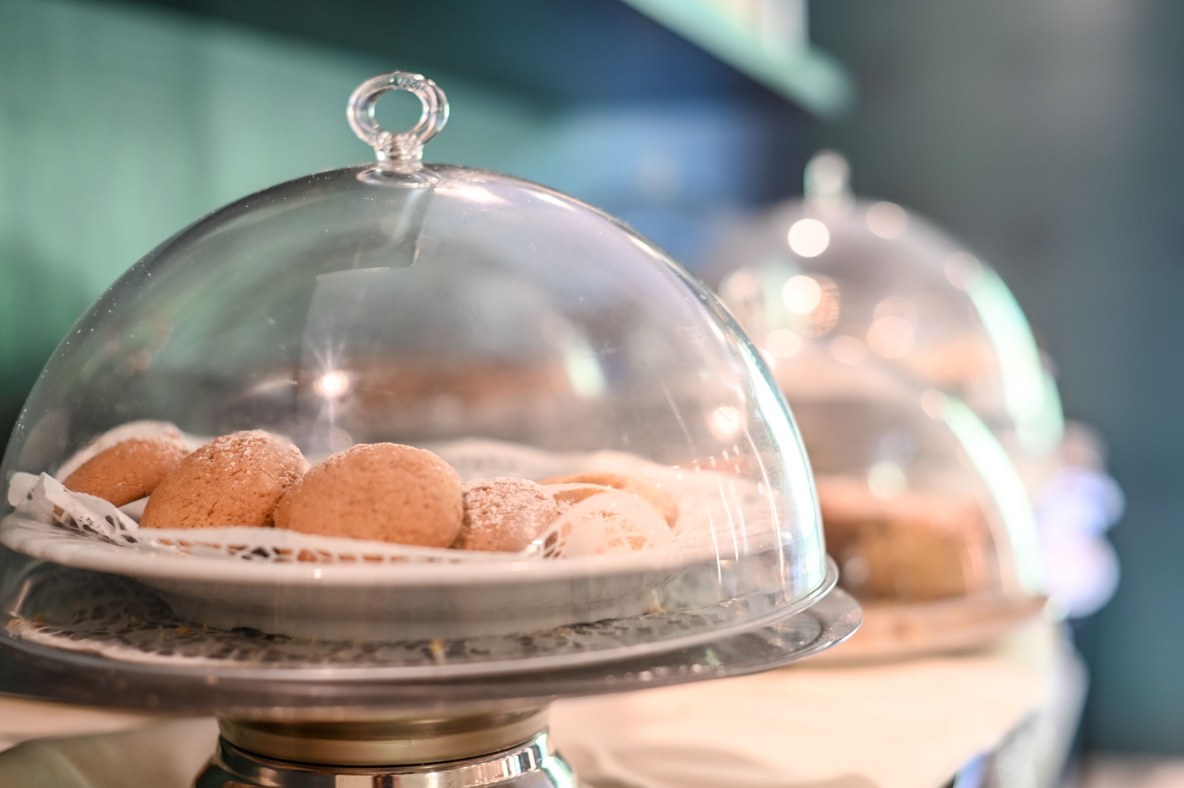 A glass dome-covered dessert display with various pastries.
