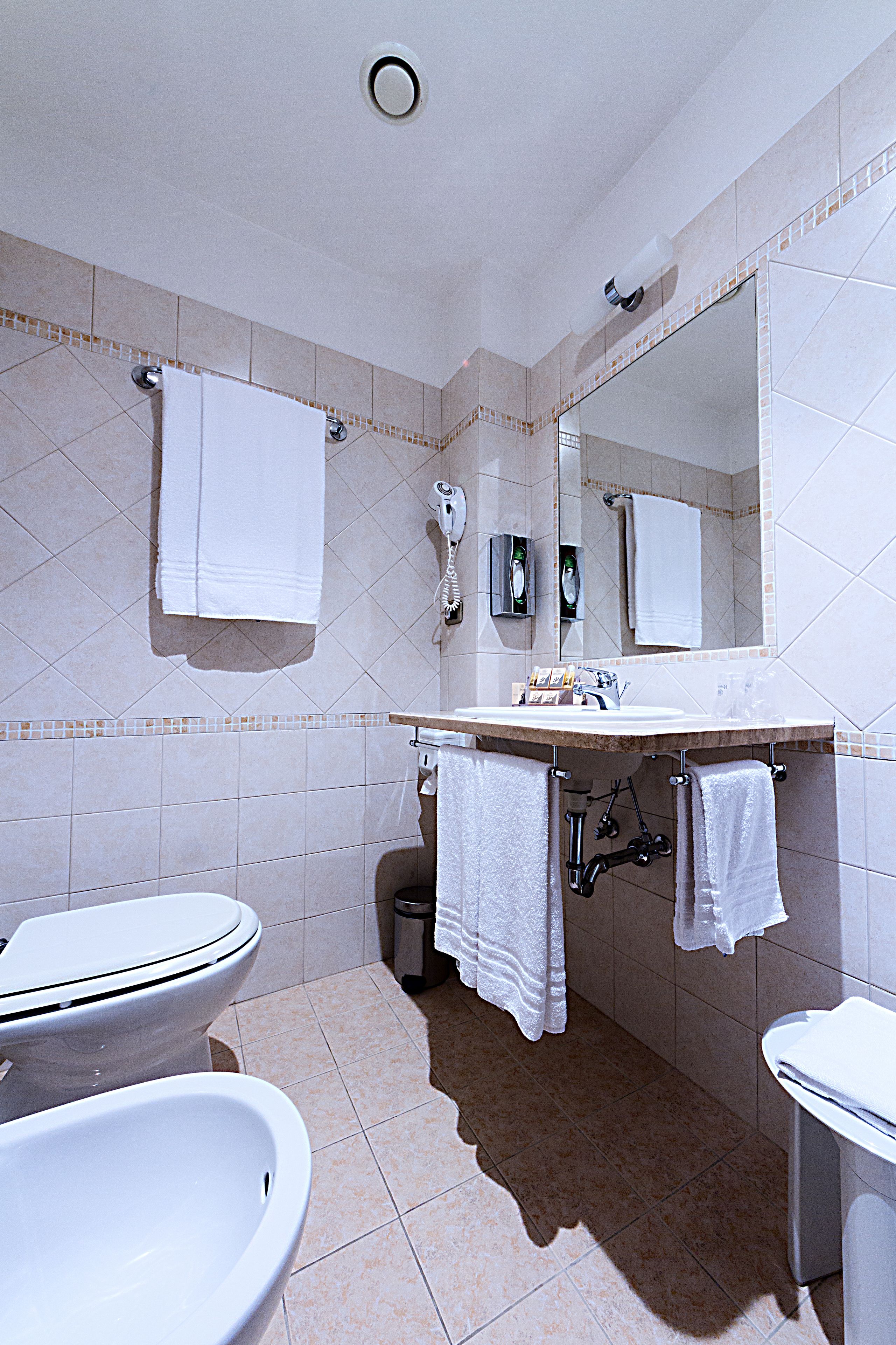Ein Badezimmer mit Toilette, Bidet, Waschbecken und Spiegel.