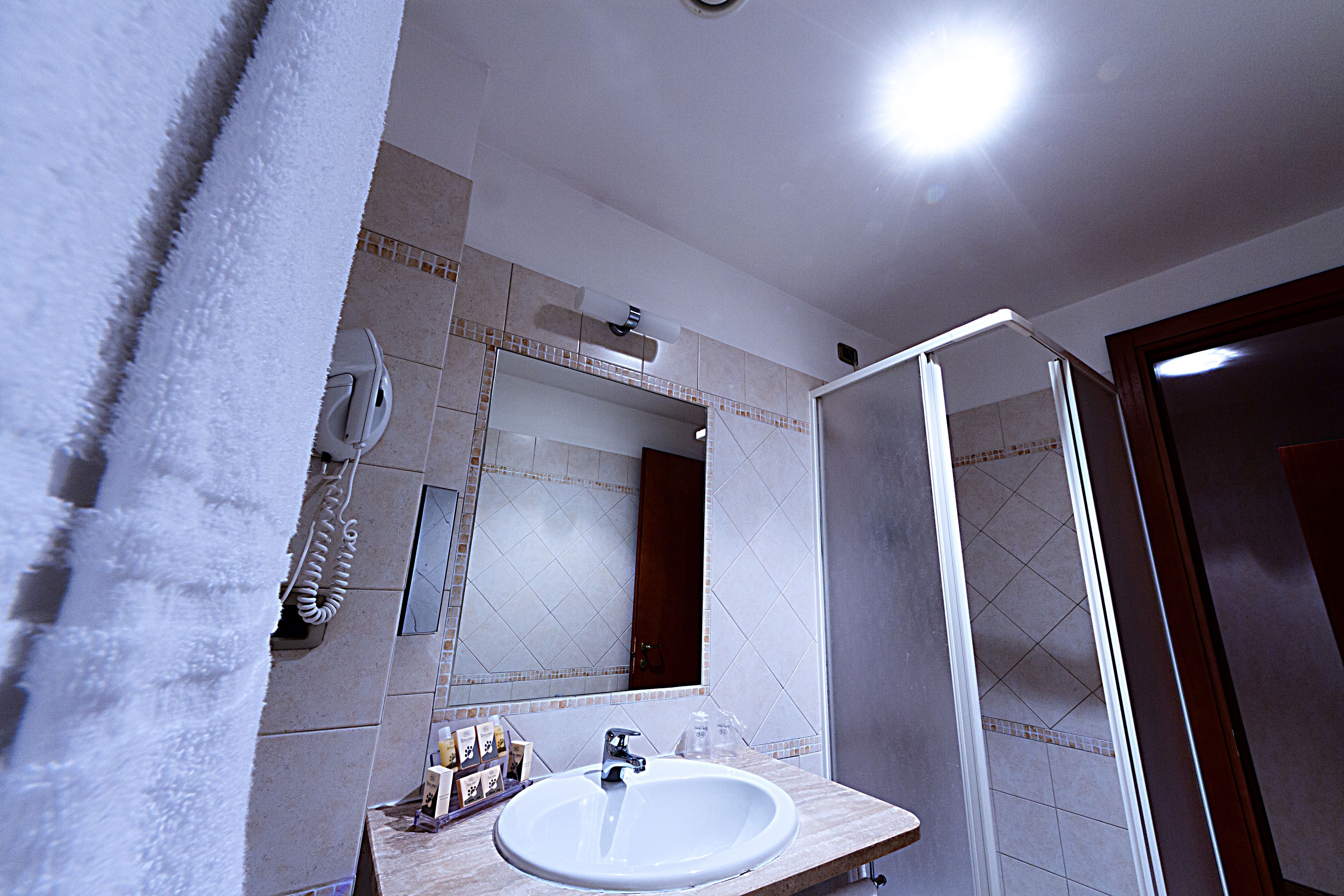 A bathroom with a white sink, mirror, and shower.