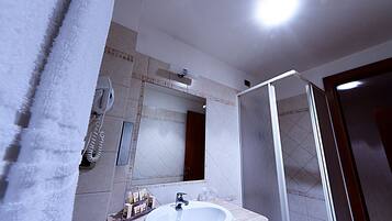 A bathroom with a white sink, mirror, and shower.