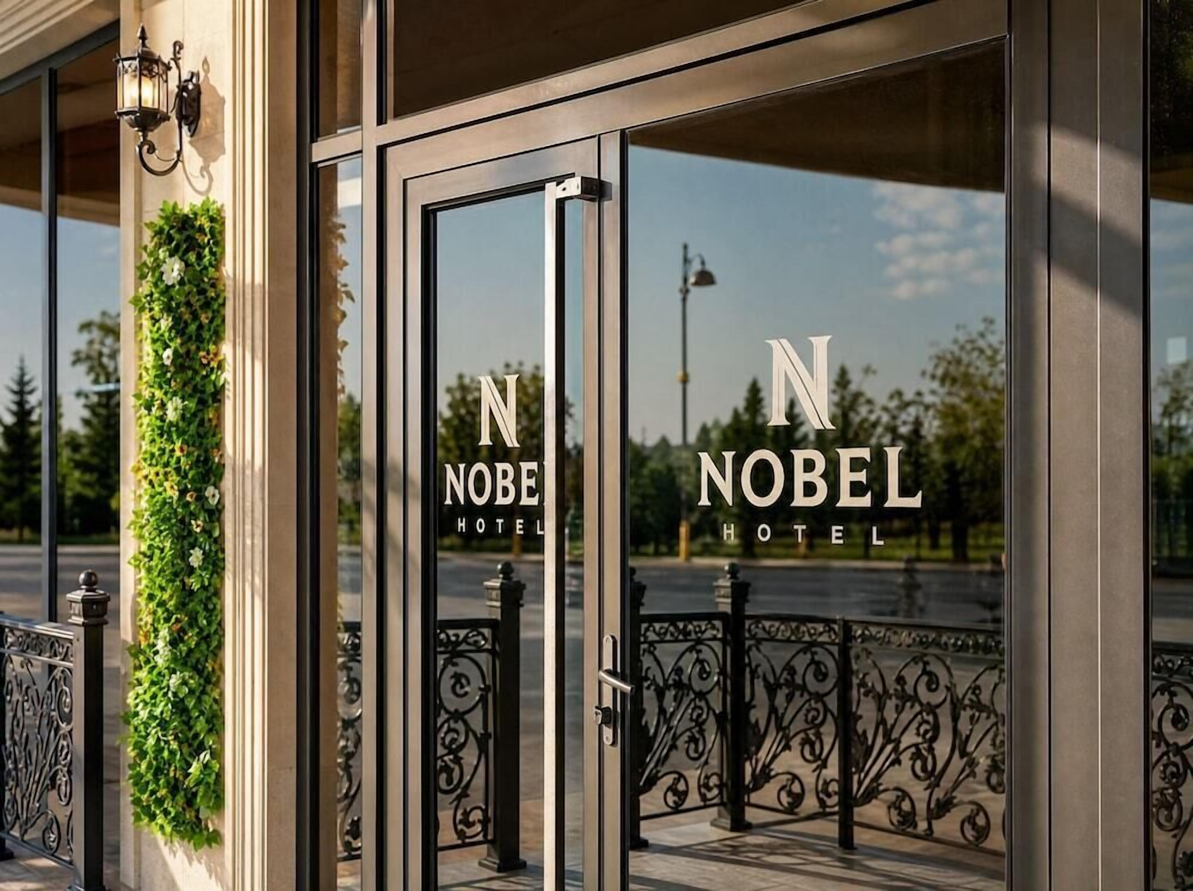 The entrance of the Nobel Hotel with a glass door and a metal gate.