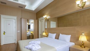 A hotel room with a large bed, bedside lamps, a mirror, and a wardrobe. - Nobel Hotel (Baku)
