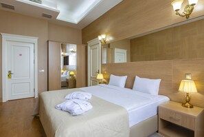 A hotel room with a large bed, bedside lamps, a mirror, and a wardrobe. - Nobel Hotel (Baku)