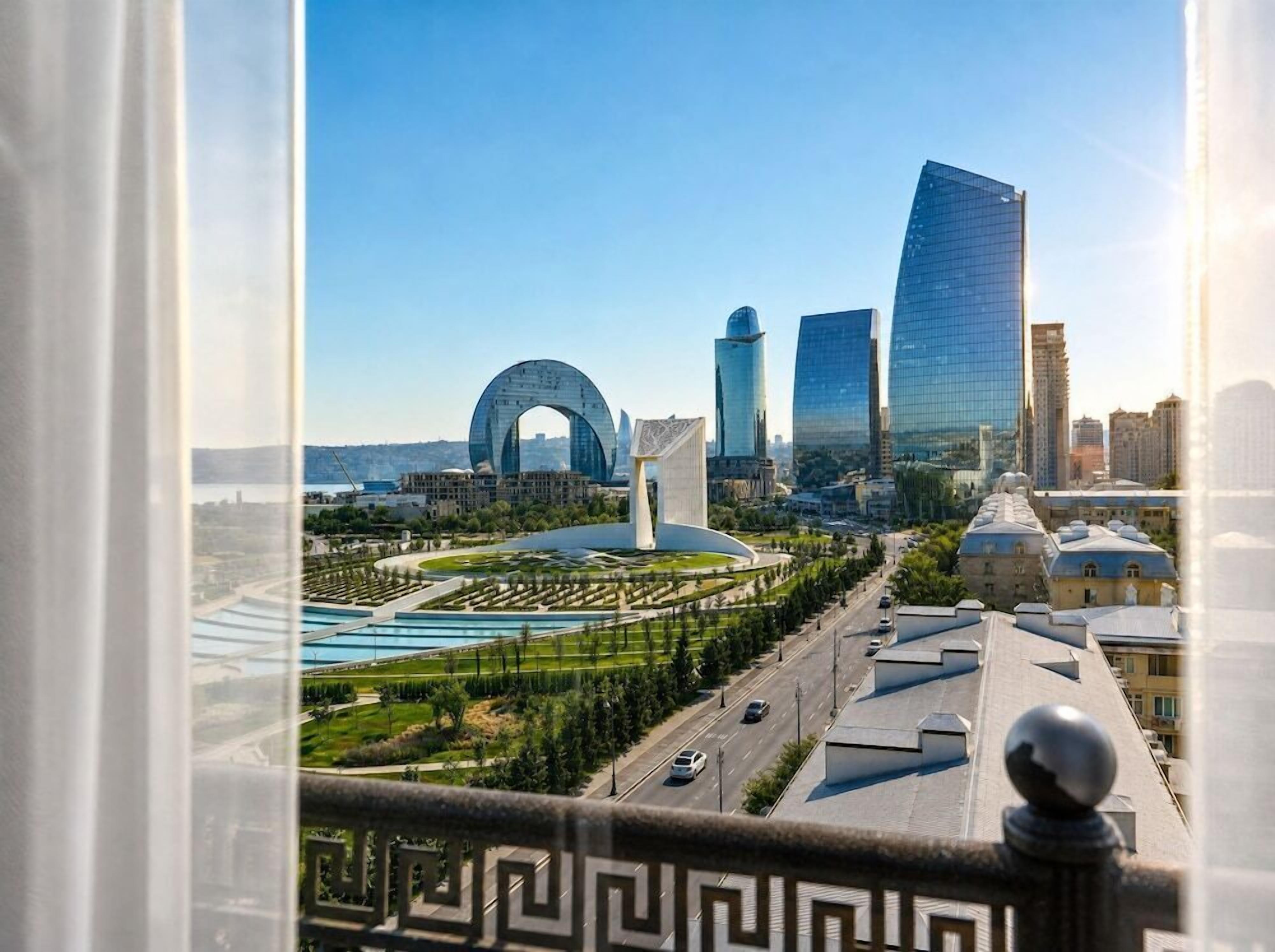 A cityscape with modern buildings, a large arch structure, and a well-maintained park area.