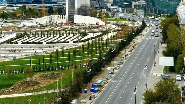 A modern cityscape with prominent glass buildings, a large circular structure, and a well-maintained road with vehicles. - Nobel Hotel (Baku)