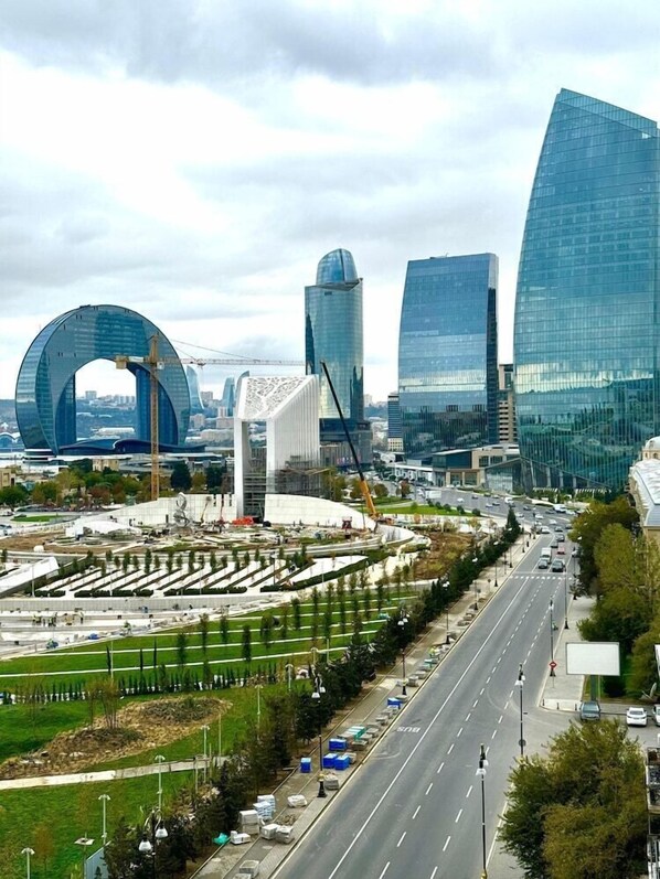 A modern cityscape with prominent glass buildings, a large circular structure, and a well-maintained road with vehicles. - Nobel Hotel (Baku)