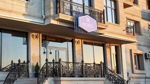 A hotel with a prominent "Nobel Hotel" sign, a grand entrance with a staircase, and a balcony with ornate metal railings. - Nobel Hotel (Baku)